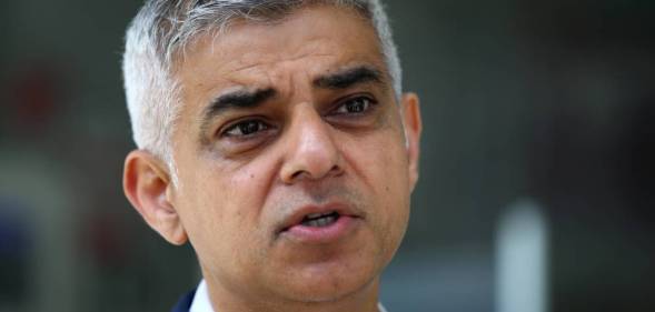Sadiq Khan, the Mayor of London, wears a white collared shirt with a blue jacket as he stares slightly off camera
