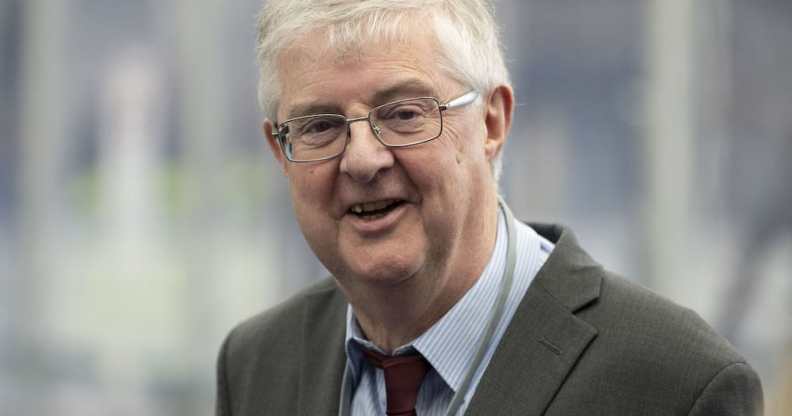 A photo shows first minister of Wales Mark Drakeford wearing a grey suit jacket, white shirt, red tie and glasses as he smiles at the camera