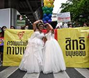 A same-sex couple poses in wedding dresses as members of the LGBTQIA+ community take part in the Pride March in Bangkok, Thailand