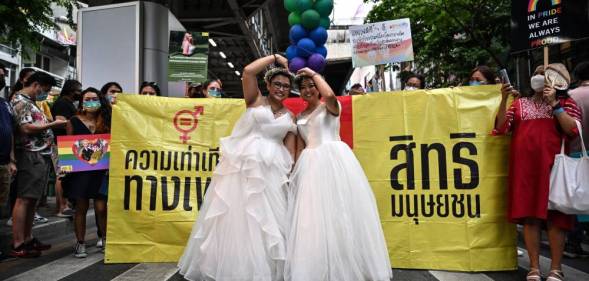 A same-sex couple poses in wedding dresses as members of the LGBTQIA+ community take part in the Pride March in Bangkok, Thailand