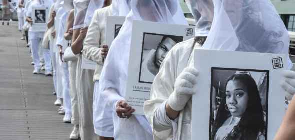 People wearing all white hold up signs of mass shooting victims, including Pulse