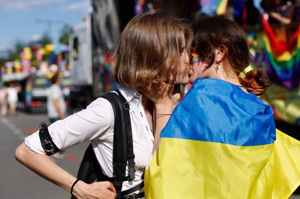 Two women, one of them wrapped into a Ukrainian flag, kis