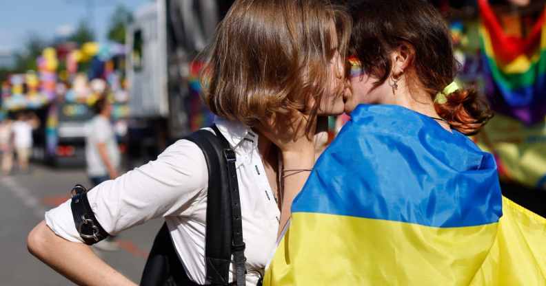 Two women, one of them wrapped into a Ukrainian flag, kis