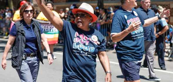 Black Chicago mayor, Lori Lightfoot, waving to Pride crowds in Chicago, with wife, Amy Eshleman, by her side.