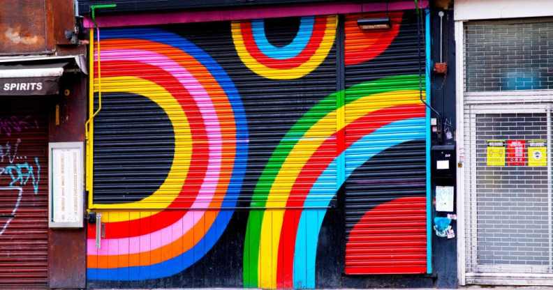 Dalston Superstore's exterior shutter, decorated in colourful rainbow display of colours. On either side are other small, lcoal London businesses.