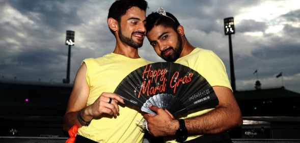Two 2022 Mardi Gras volunteers pose together holding a fan, while wearing lemon yellow t-shirts.