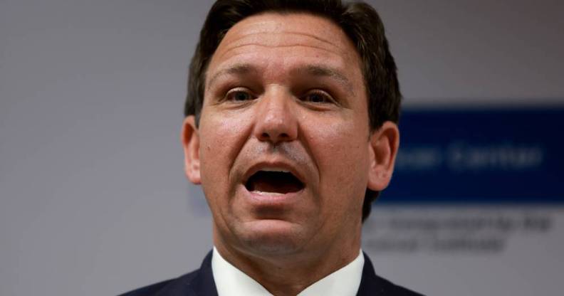 Florida governor Ron DeSantis wears a white button up shirt, light blue tie and dark blue jacket as he speaks to someone off camera