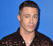 Colton Haynes wears a brown sequinned shirt as he stands in front of a blue background
