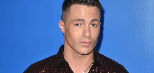 Colton Haynes wears a brown sequinned shirt as he stands in front of a blue background