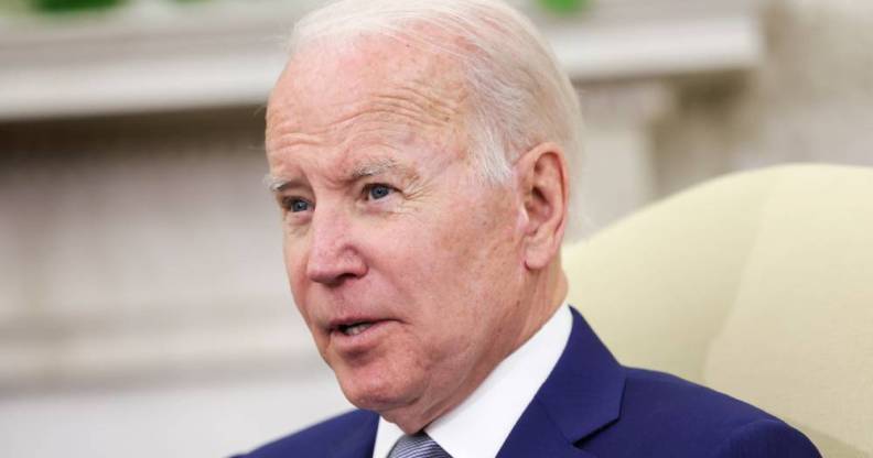 President Joe Biden stares off camera as he speaks to someone. He is wearing a white button up shirt, blue suit jacket and blue tie