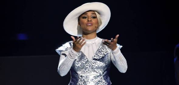 Ariana DeBose wears a white hat, white outfit and silver sequinned top as she sings on stage during the 2022 Tony Awards
