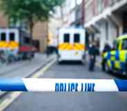 Police officers and vans behind safety police line tape.