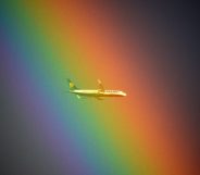 A plane of the Irish low cost company Ryanair flies in front of a rainbow