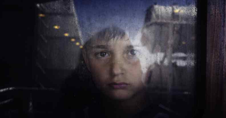 A young boy looks out through a window