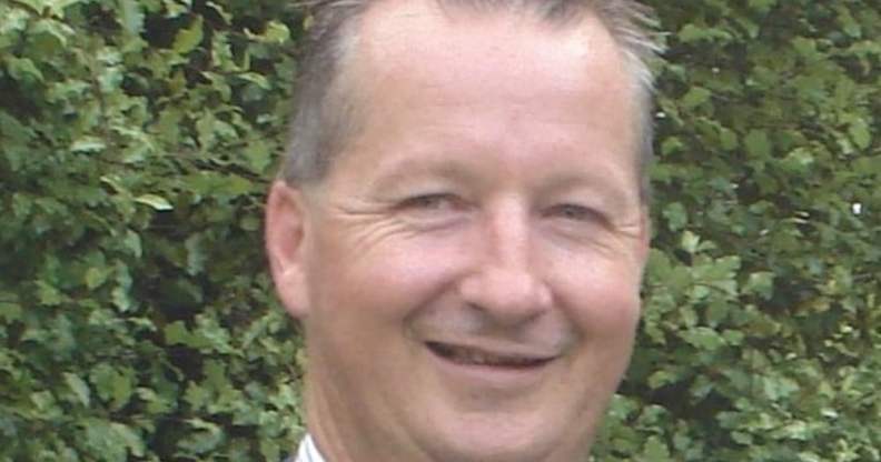 A headshot of Peter Keeley smiling in front of a bush