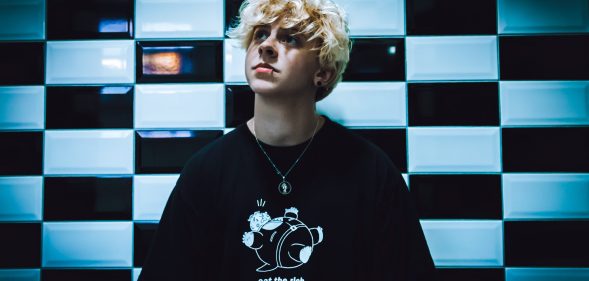 NOAHFINNCE against a wall of black and white checkerboard tiles