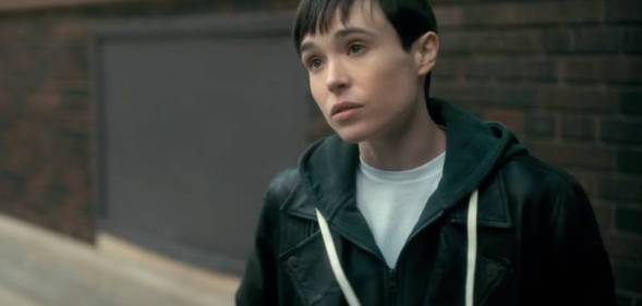 Elliot Page appears as his character from the Netflix show The Umbrella Academy. The character, Viktor, is wearing a white t-shirt and blue hooded sweatshirt as he stands outside and talks to someone off screen