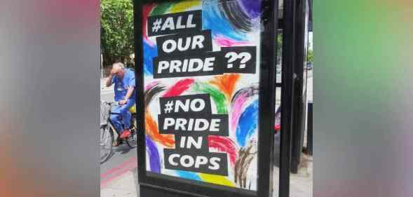 A colourful sign reading 'All Our Pride?? No Pride in Cops' is displayed outside a bus stop in London