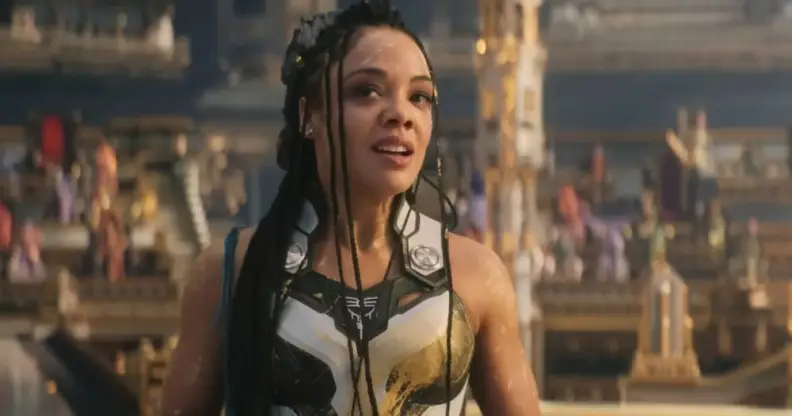 Tessa Thompson wears blue and white patterned armour as she stands in front of a crowded stadium as she plays the character Valkyrie in Thor: Love and Thunder