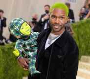 Frank Ocean, with green hair, holding a doll with a green face