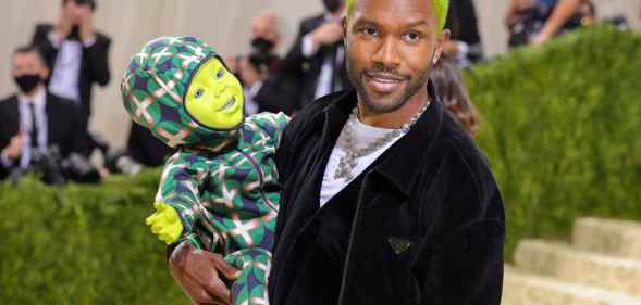 Frank Ocean, with green hair, holding a doll with a green face