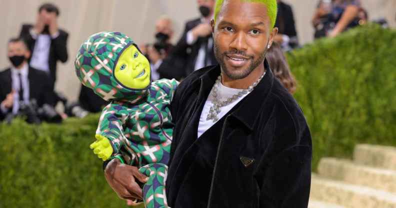 Frank Ocean, with green hair, holding a doll with a green face