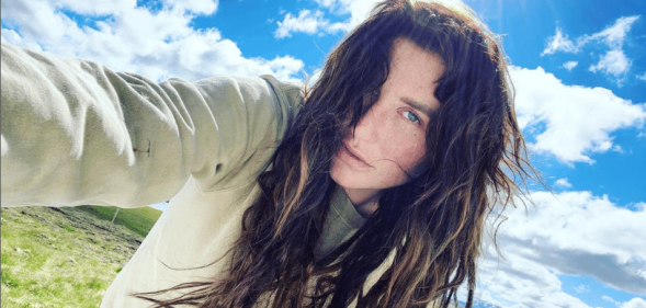 A selfie of Kesha. She's holding the camera, wearing a light hoody, standing in front of a blue but cloudy sky