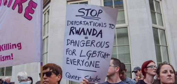 A protester holds a placard describing the Rwanda deportations as dangerous for LGBTQ people during a demonstration.