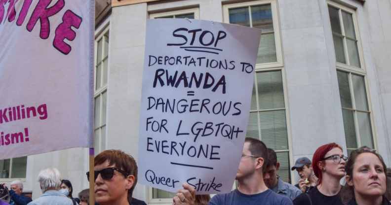A protester holds a placard describing the Rwanda deportations as dangerous for LGBTQ people during a demonstration.