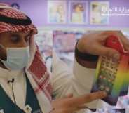 A Saudi Arabian official gestures towards a rainbow toy