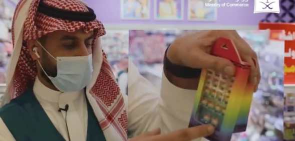 A Saudi Arabian official gestures towards a rainbow toy