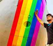 Trans pilot Adam Harry rests his hand on a rainbow painted aeroplane