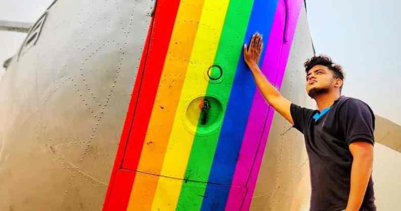 Trans pilot Adam Harry rests his hand on a rainbow painted aeroplane