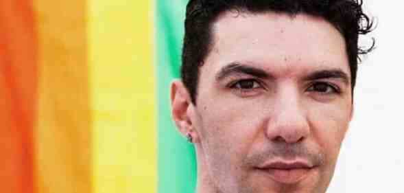 Zak Kostopoulos in front of a Pride flag