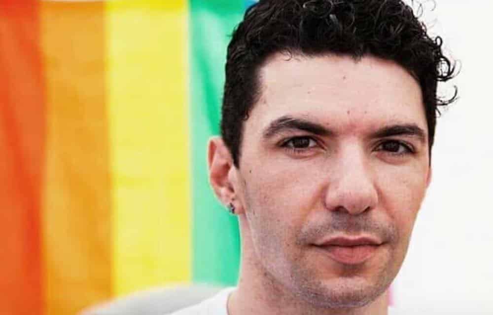 Zak Kostopoulos in front of a Pride flag