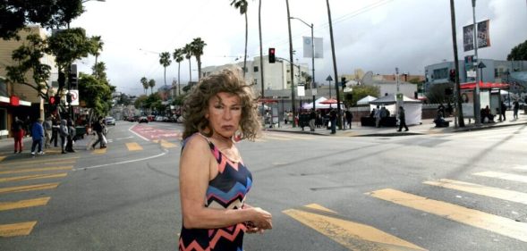 Donna in a multicoloured dress standing on a road