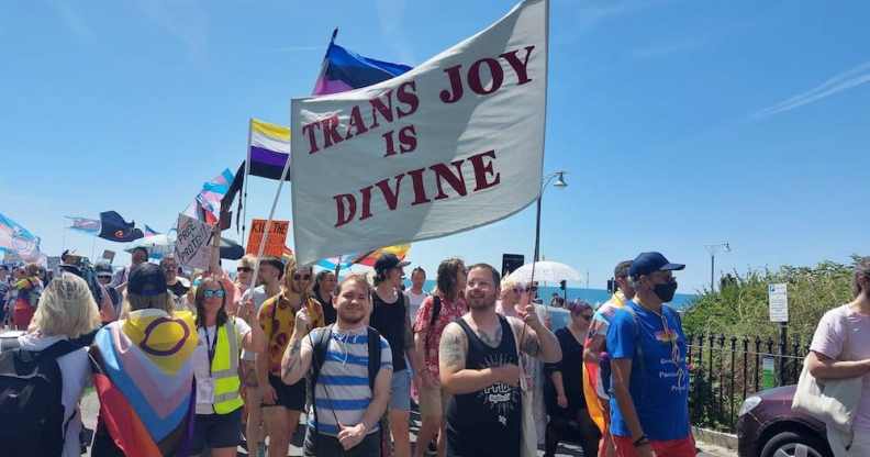 A protester holds a flag that reads 'trans joy is divine' at Trans Pride Brighton
