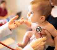 A doctor places a stethoscope on a baby
