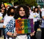 An LGBTQ+ protester carries a sign reading: 'Oppose Don't Say Gay'