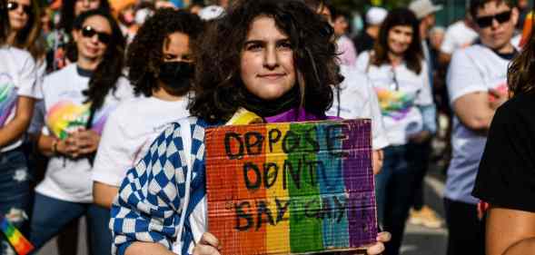 An LGBTQ+ protester carries a sign reading: 'Oppose Don't Say Gay'