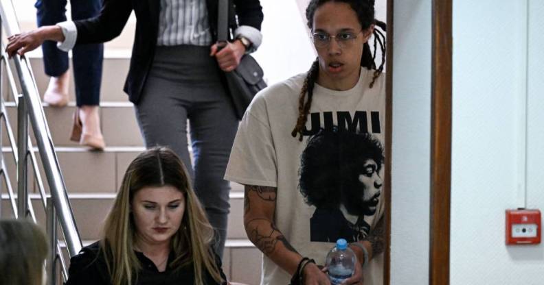 Brittney Griner wears a white t-shirt as she is handcuffed to another a person and led to a trial hearing in Russia