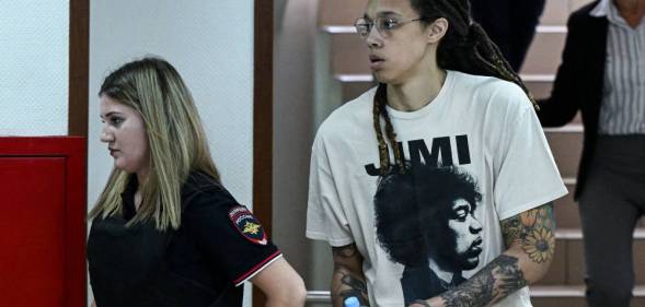 Brittney Griner wears white t-shirt as she is led out in handcuffs to a trial hearing in Russia