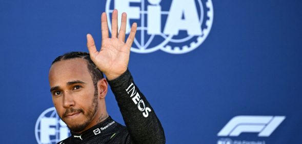 Lewis Hamilton waves as he walks back to the pits