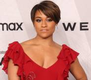 Ariana DeBose wears a red dress with frills on the sleeves as she stands in front of a white background with black logos for HBO Max and Westworld