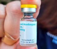 A person holds up a vile of a vaccine with the white label reading monkeypox
