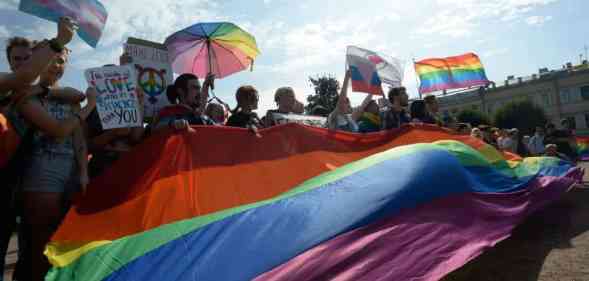 Activists wave rainbow flags during the gay pride rally in Saint Petersburg, Russia. The poeple hold up signs protesting against 'gay propaganda' laws and demanding change for the LGBTQ+ community