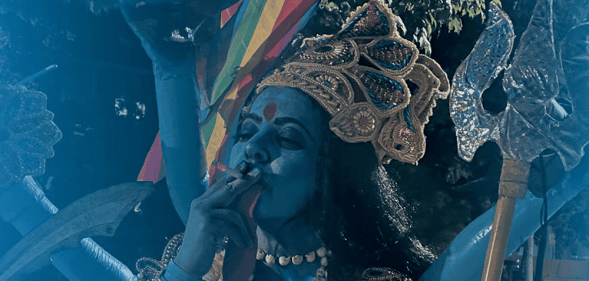 The poster for the upcoming documentary film Kaali, depicting a woman dressed as the goddess smoking a cigarette and holding a Pride flag