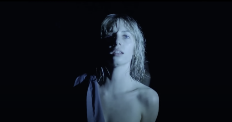 Maya Hawke in "Thérése" music video shirt half on with black backdrop