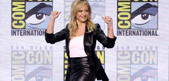 Sarah Michelle Gellar at Comic-con announcing Wolf Pack news in white shirt and black blazer and pants.