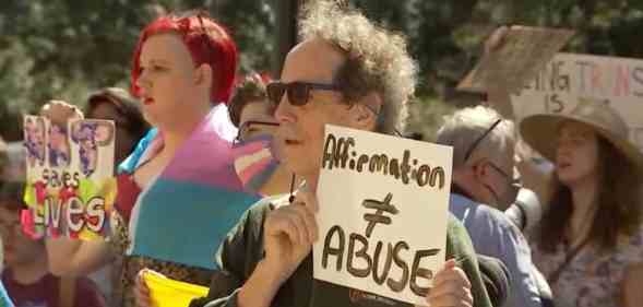 A person holds up a sign that reads 'Affirmation ≠ abuse' in protest of Texas officials investigating the families of trans youth for 'child abuse'